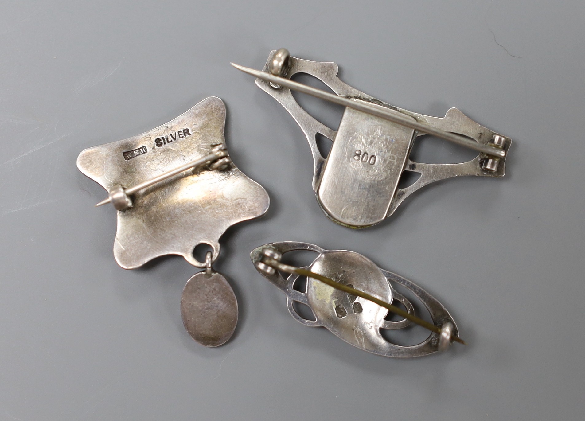 An early 20th century sterling and enamel set drop brooch, maker's mark only for William Hair Haseler, 33mm, a similar silver and enamel navette shaped brooch by Charles Horner and one other 800 white metal and enamel br
